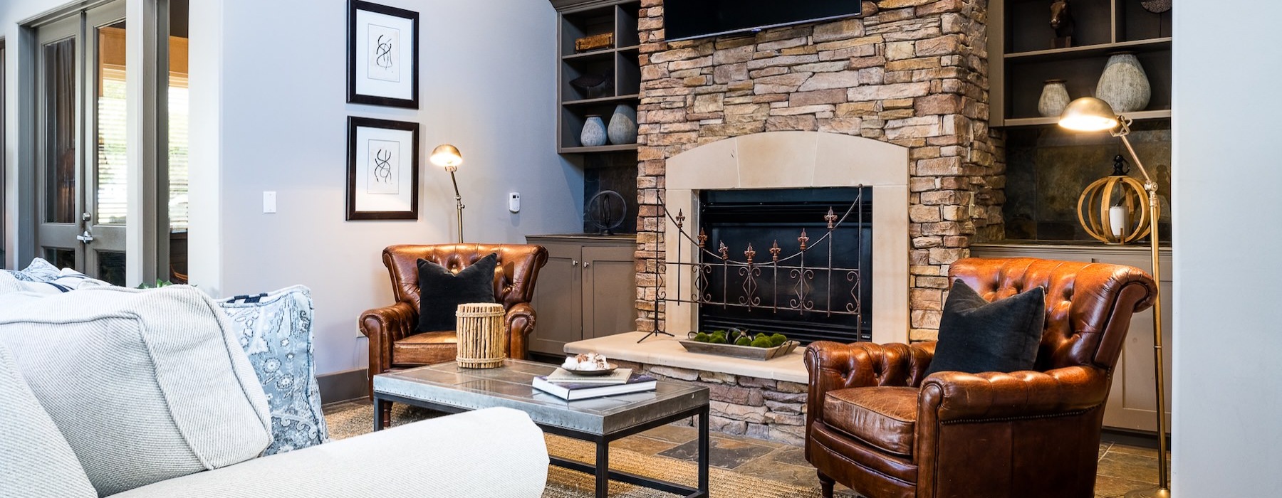 a lounge with a couch, chairs, tv and a fireplace