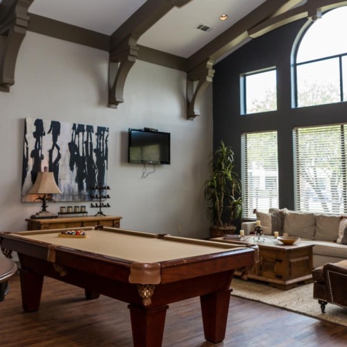 a lounge with a pool table, tv's and a couch